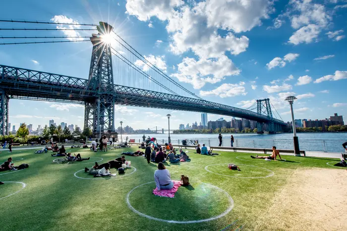 A view of the Williamsburg Bridge with people in Domino Park